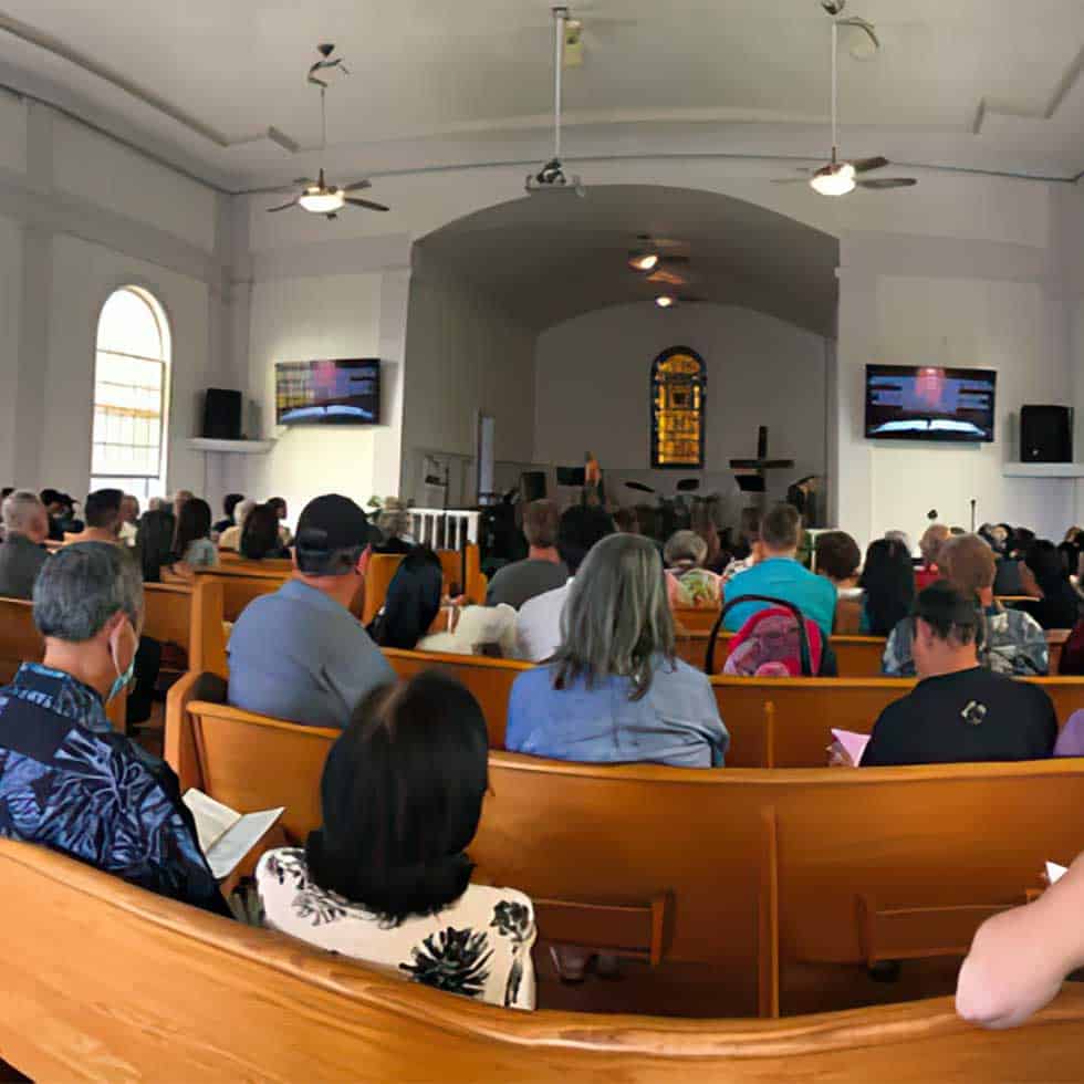 Congregation seated in wooden pews during a worship service inside The Church at Koloa sanctuary.